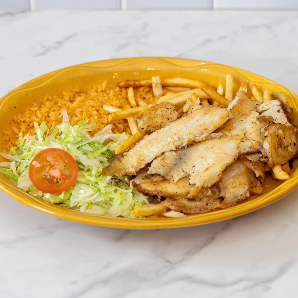 La Unica's fried fish platter with rice, french fries, shredded lettuce, and a tomato slice.