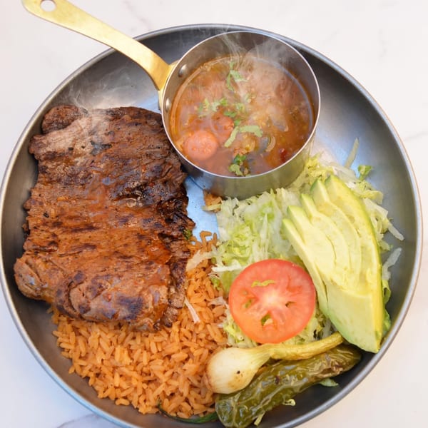 La Unica Mexican Restaurant's carne asada with rice, soup, avocado, tomato, and grilled vegetables.