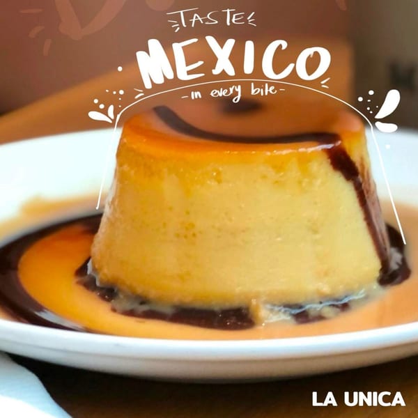 A golden flan dessert with dark caramel sauce on a white plate from La Unica Mexican Restaurant.